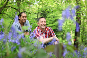 A woman and a man smiling amongst bluebells